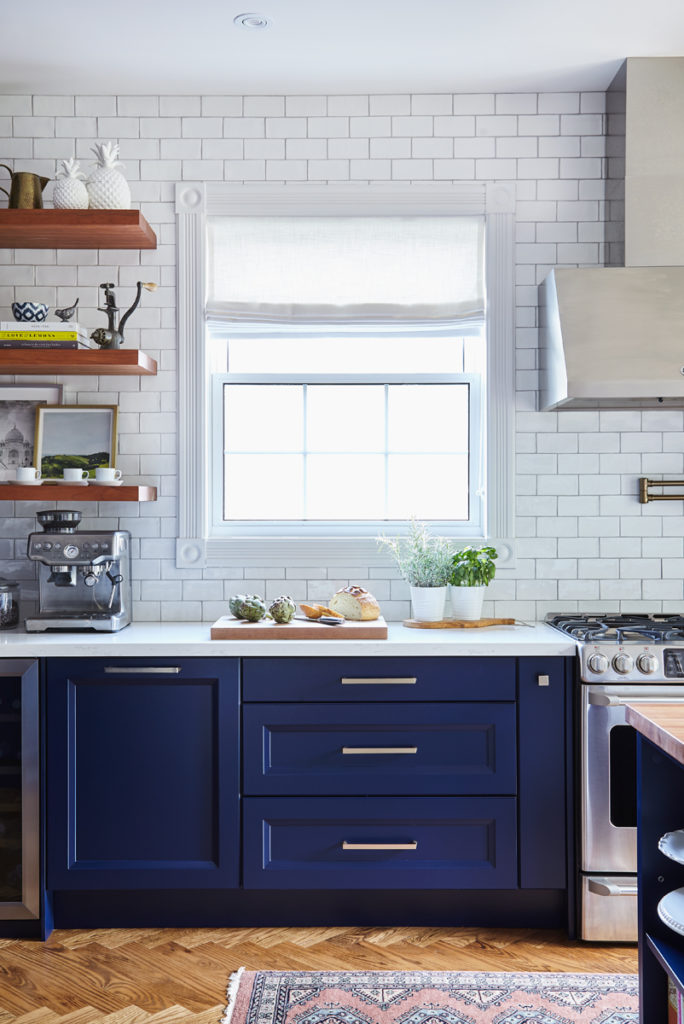 beautiful kitchen with navy blue cabinets, gold hardware, and white subway tile backsplash 