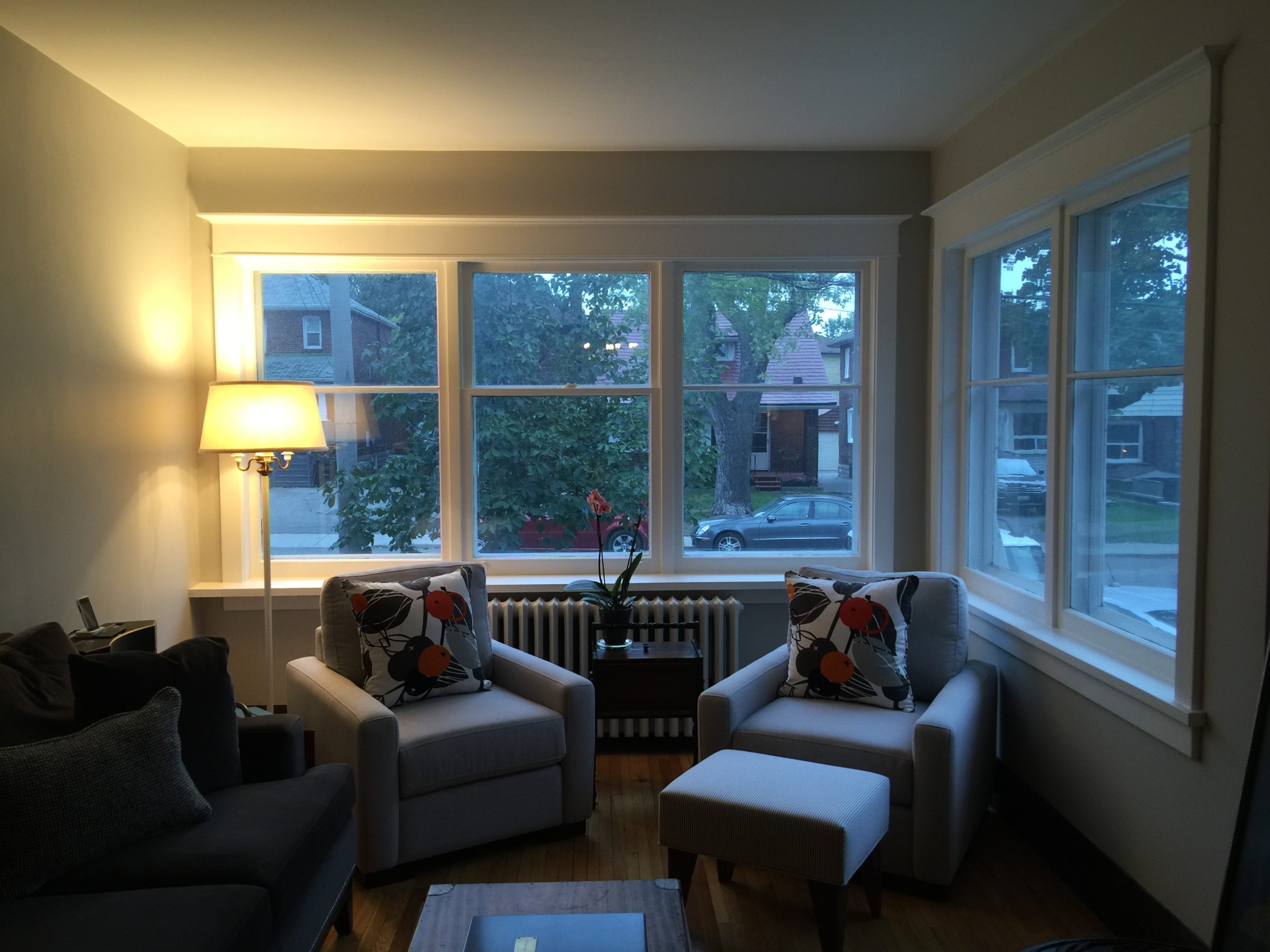 before photo of dark living room in Toronto home with dark grey sofa, grey chairs, and an old lamp in the corner