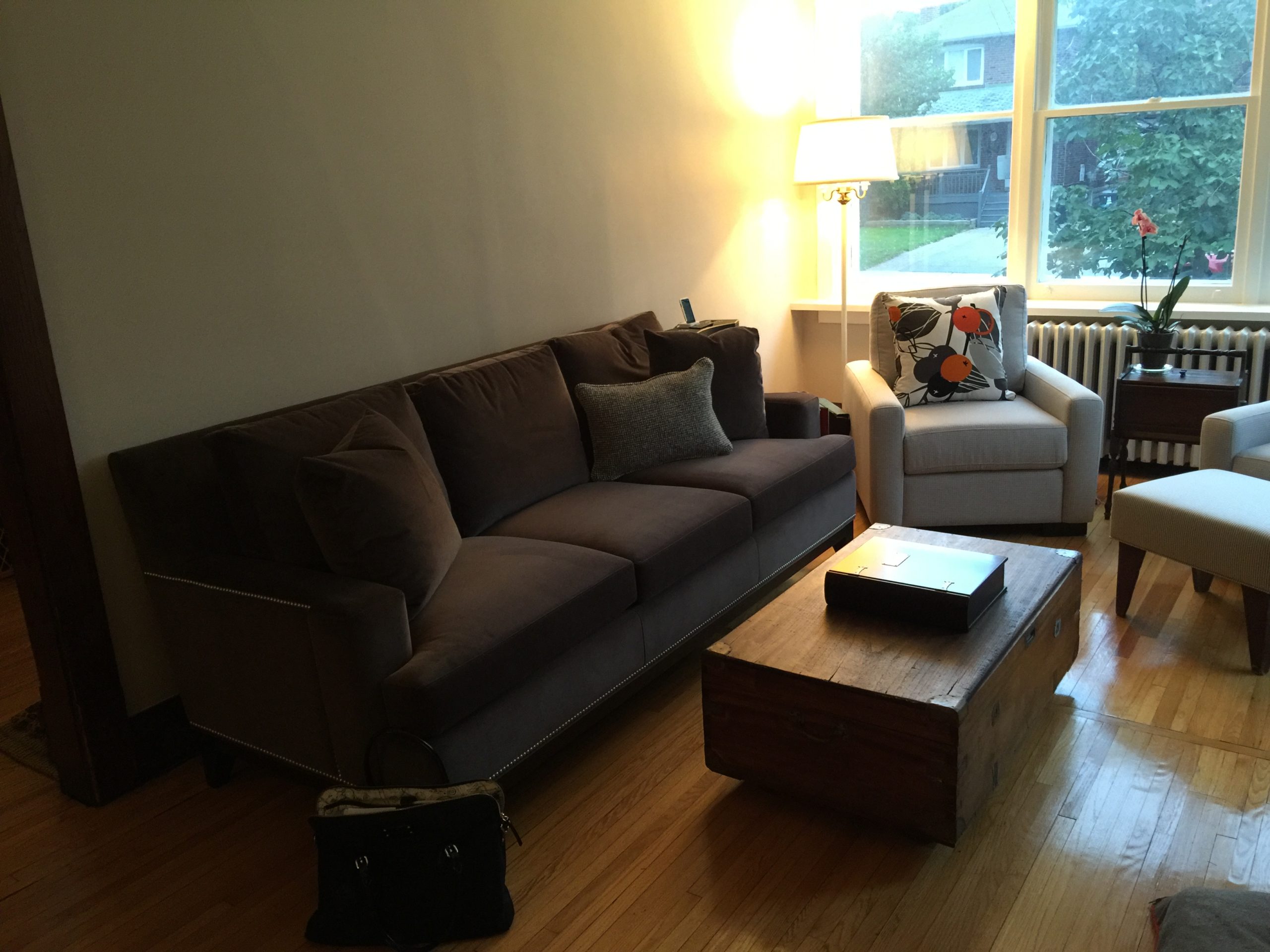 before photo of living room with dark grey sofa, an old lamp in the corner, and small brown coffee table