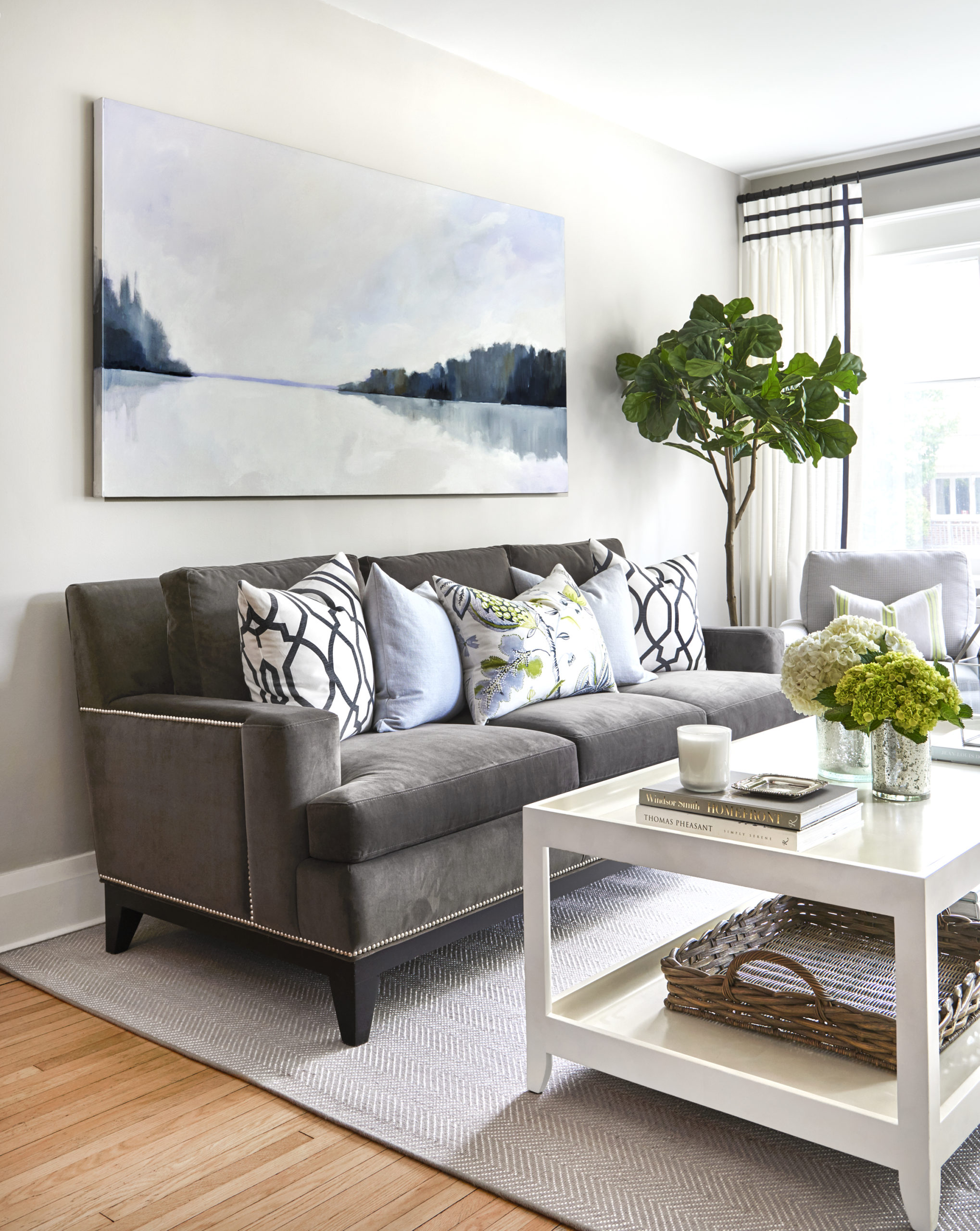 living room with grey velvet sofa, decorative pillows, and original artwork hung above the sofa