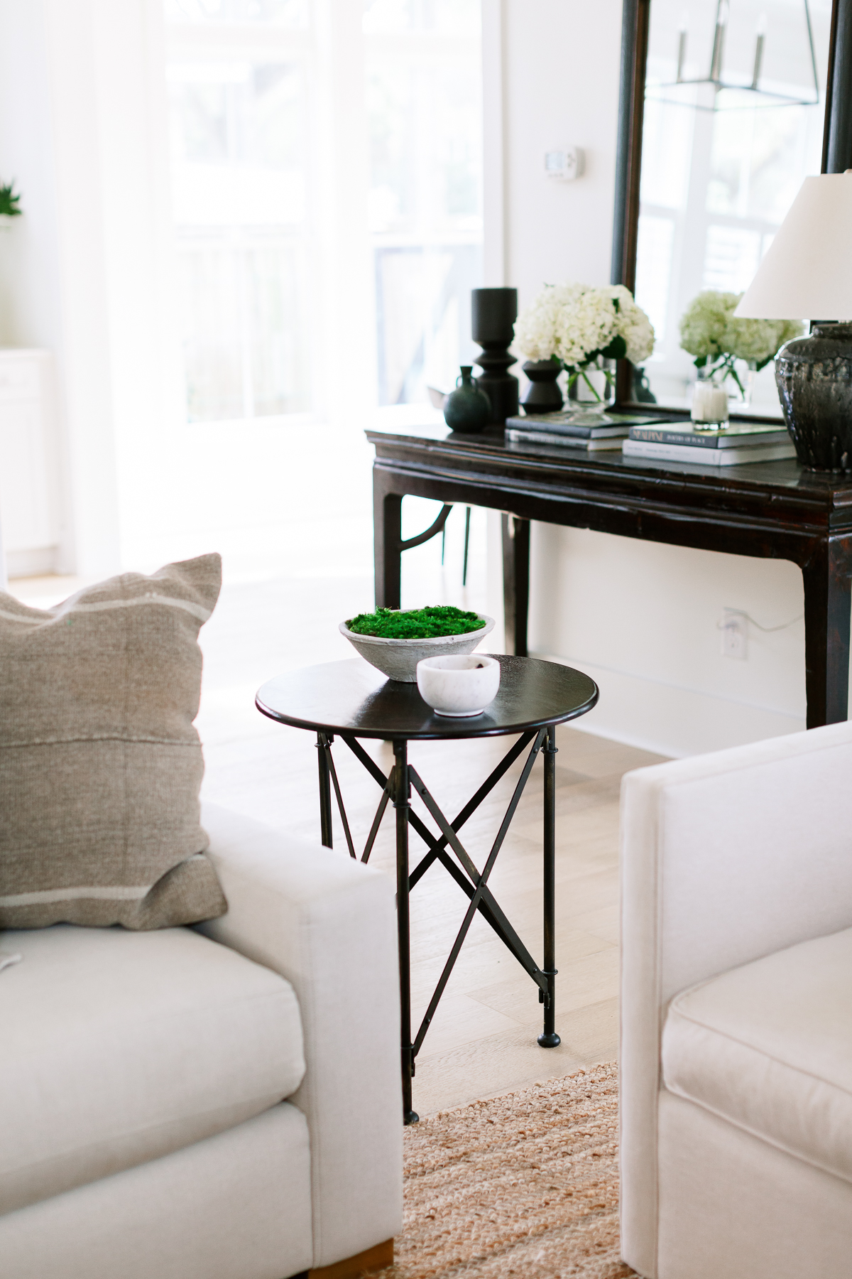 corner of living room with two white armchairs and a black side table