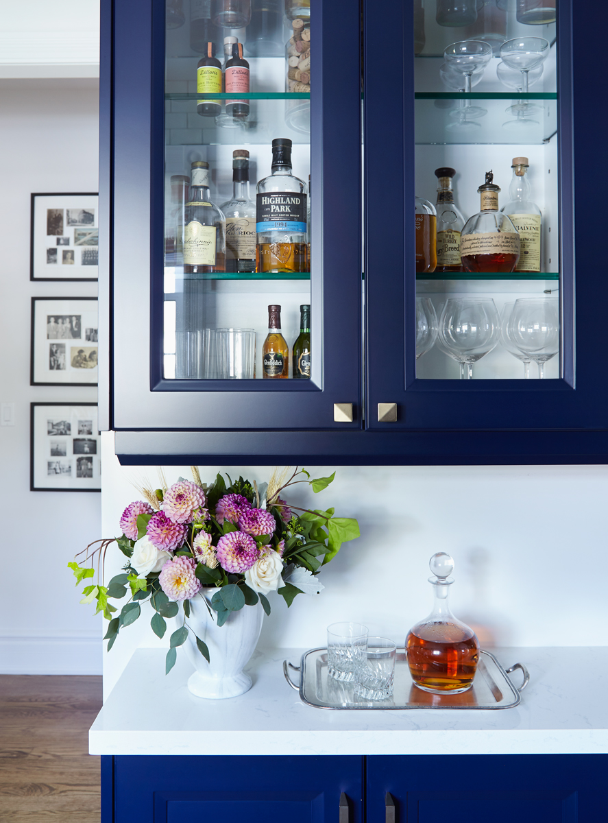 Bar area in kitchen with navy cabinets, white counter, and a beautiful flower arrangment