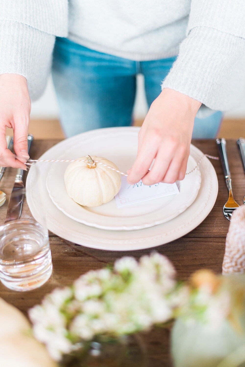 hands tying a bow on a pumpkin to decorate a tabletop