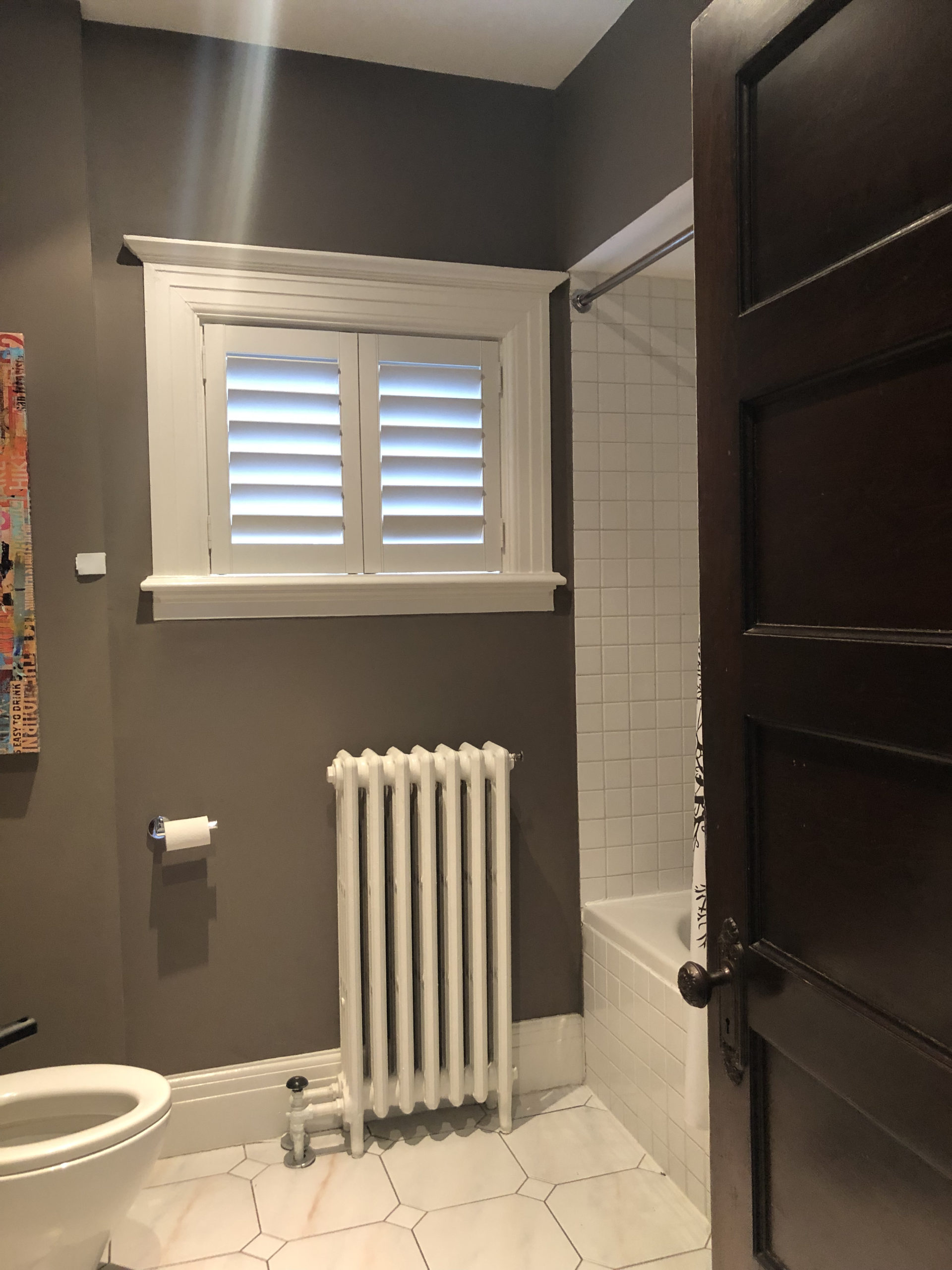 before photo of bathroom, dark room with tub and radiator under window